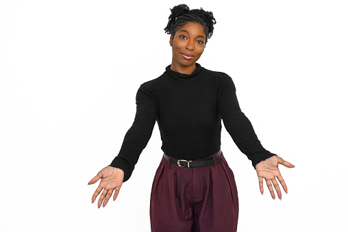 Friendly African American woman in studio Female model in black long sleeve shirt and trousers smiling and hugging camera. Portrait, emotion concept