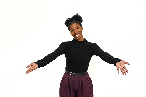 Outgoing African American woman in studio Female model in black long sleeve shirt and trousers smiling and hugging camera. Portrait, emotion concept