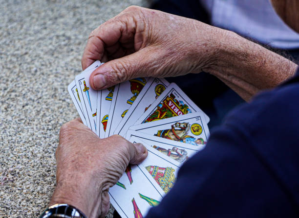 hände einer älteren person, die karten aus einem deck spanischer karten auswählt - playing chance gambling house stock-fotos und bilder