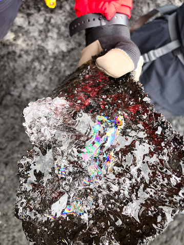 Holding a piece of glacier ice Glacier with Rainbow reflections Sólheimajökull Glacier Southern Iceland