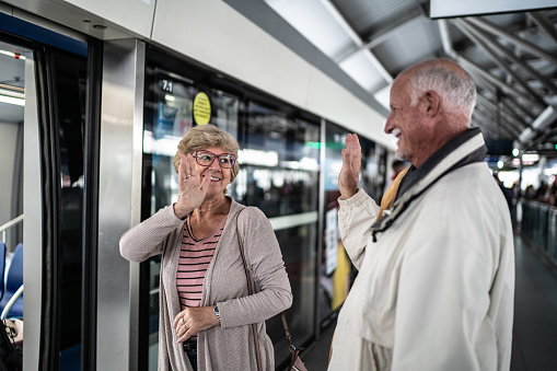 Senior couple waving goodbye on the subway platform