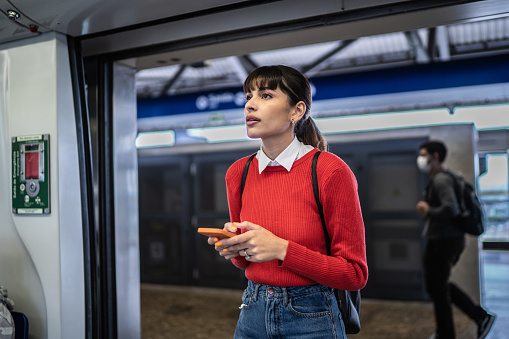 Young woman using smartphone entering in the subway train