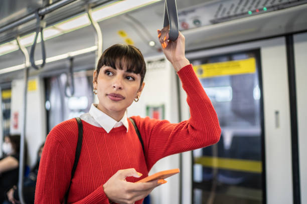 junge frau, die das handy in der u-bahn benutzt - train subway station people subway train stock-fotos und bilder