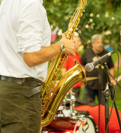 Saxophonist in the process of playing the saxophone during a performance at a street festival.