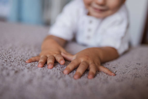 istock Close-up of toddler's hands on a bed 1423137541