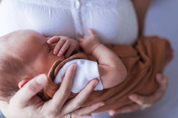 istock Baby covering face sleeping in mother's  arms 1423137557