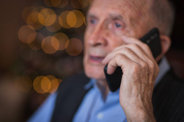 Close-up of an old man talking via smartphone at home