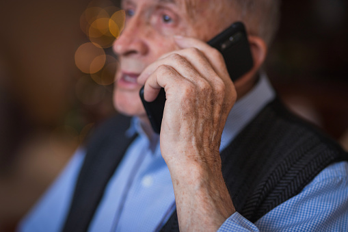 Close-up of a senior man talking via phone at home
