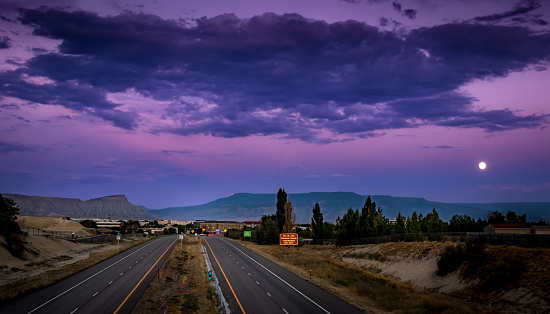 Beautiful sunset picture of Interstate I70, Grand Junction, Colorado with Mount Garfield and Grand Mesa in the background and a full moon rising.