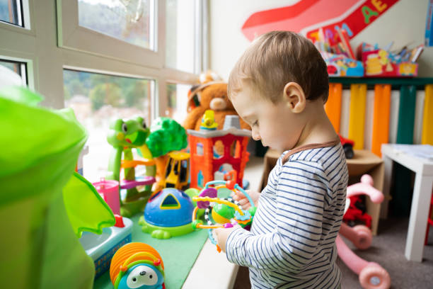 menino brinca com brinquedos educativos no quarto das crianças. o estudo das cores e o desenvolvimento da tato. criança de um ano e meio, dois anos. foco seletivo - 18 a 23 meses - fotografias e filmes do acervo