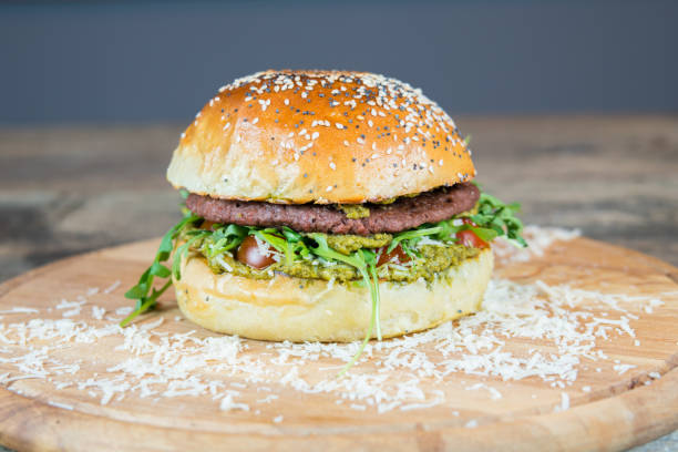 Vegan hamburger with no meat alternative. Plant based with pesto, vegan cheese and frying potatoes. Healthy street and fast food. Homemade burger and bun. Tasty and full of proteins. American culture.