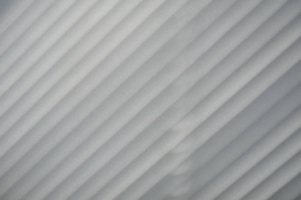 istock Diagonal blinds shadow on a white plastered wall, black and white style backdrop 1423145603