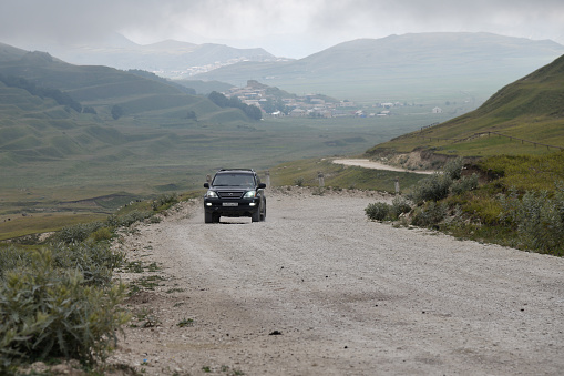 Dagestan, Russia - July 23, 2022: Off-road car drives on a dirt road. Caucasus mountains. Extreme mountain safari is one of the main local tourist attractions in Dagestan