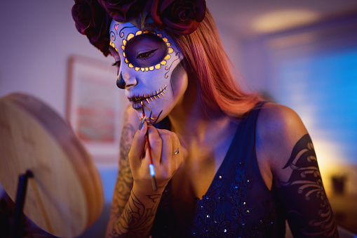 Young woman doing make-up for Day of the Dead celebration.