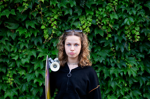 Portrait of beautiful teenage girl skateboard on green background