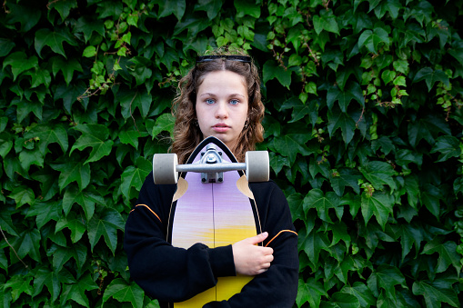 Portrait of beautiful teenage girl skateboard on green background