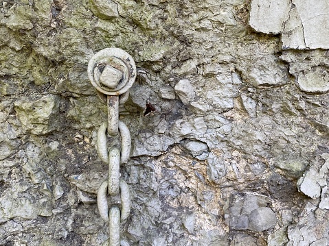 Old chain hanging off of a bolt in a crumbling concrete wall, could be used for a back ground with copy space, old and grunge