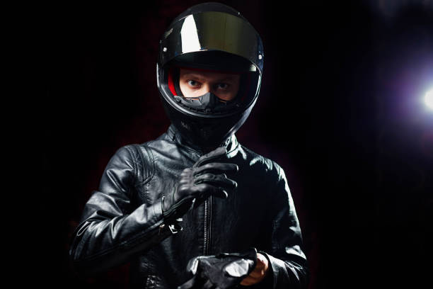 istock man in a motorcycle helmet in an outfit on a dark studio background. 1423153795