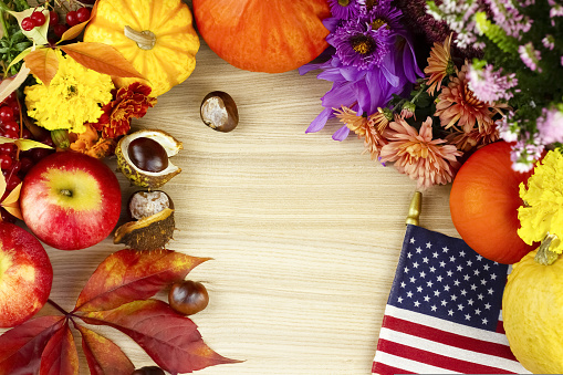 Wooden background with flowers, orange pumpkins, red leaves, chestnuts and American moisture.Thanksgiving, halloween. High quality photo