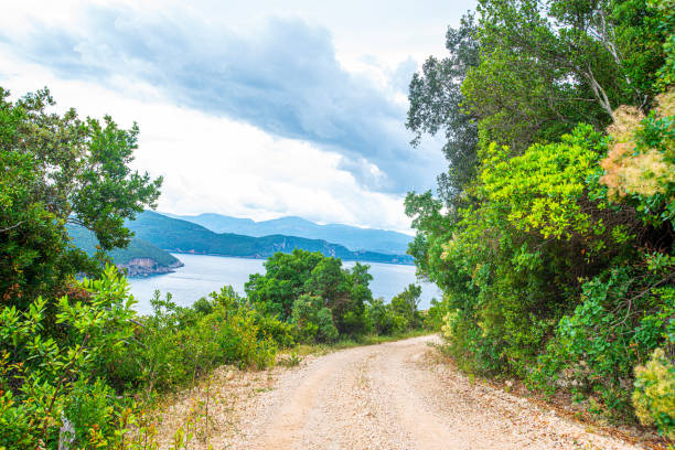 Dusty road on the Mediterranean coast over beautiful Parga city Dusty road on the Mediterranean coast over beautiful Parga city parga greece stock pictures, royalty-free photos & images