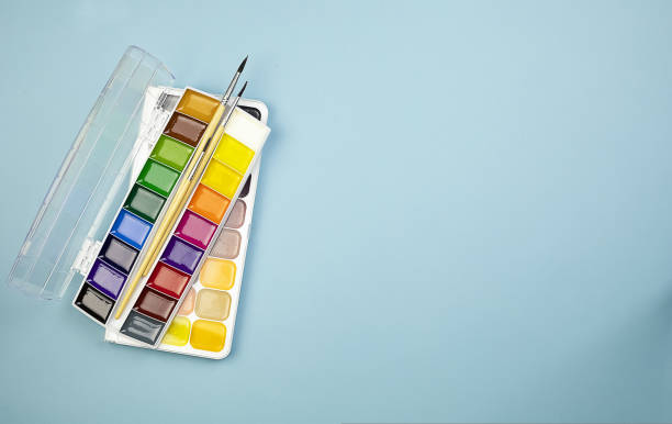 istock Watercolor paints with brushes on a blue background with copy space. 1423155890