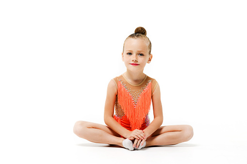 Charming sportive girl sit in studio isolated background in lotus yoga pose, wearing makeup and bright leotard, little gymnastics and acrobatics child