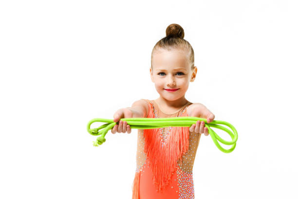 Gymnastic acrobatic athlete girl elementary school age pose with jumping rope in studio isolated background