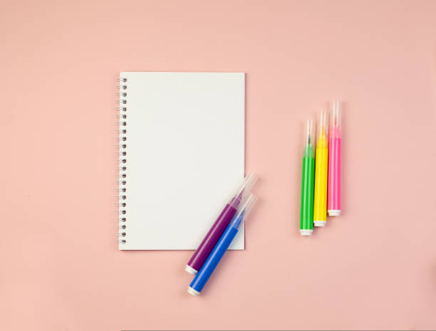 istock Notepad on a pink background with a backup for copy with multi colored markers 1423157812