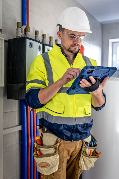 istock Man, an electrical technician working in a switchboard with fuses, uses a tablet. 1423162339
