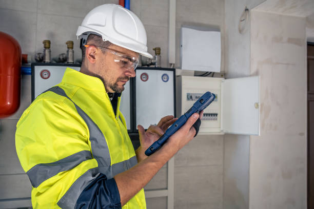 istock Man, an electrical technician working in a switchboard with fuses, uses a tablet. 1423162341