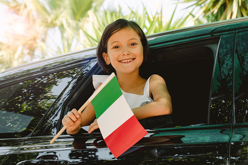 Girl holding Italian Flag in the car.