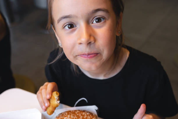 istock A little girl eats fast food in a cafe. 1423163843