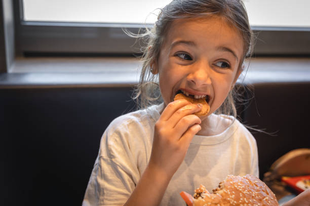 istock A little girl eats fast food in a cafe. 1423163846