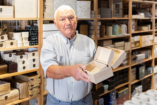 Attentive elderly consumer choosing jewelry box in furniture shop
