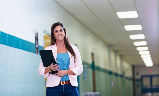 istock Female teacher standing in school hallway 1423164653