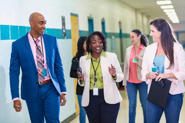 Photo of Multiracial group of teachers walking in school hallway