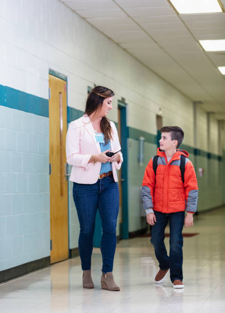 istock Elementary student walking with teacher in school hallway 1423165501