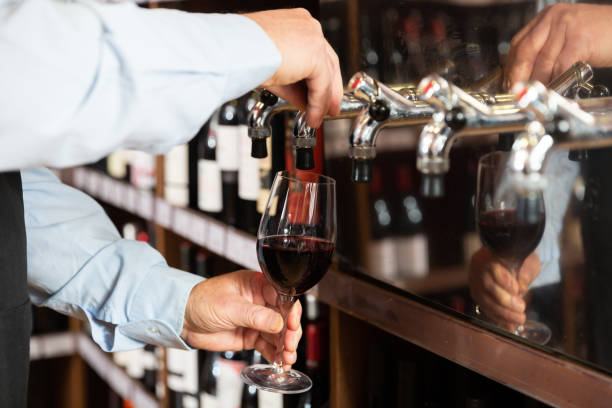 istock Hands of bartender pouring red wine from tap 1423166003