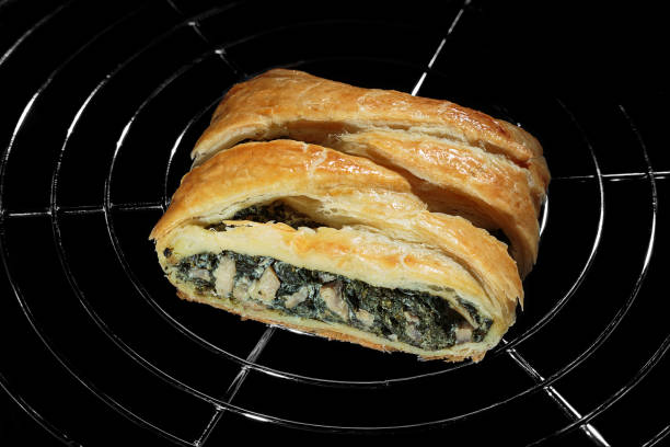 Puff pastry braid with spinach, mushrooms and lactose free cheese on black background, homemade recipe concept