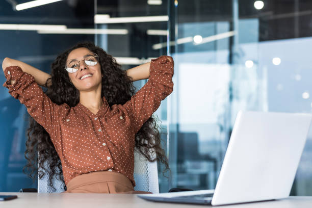 istock Young woman engineer developer programmer works in the office inside the IT company, satisfied with the work result, rests hispanic looks out the window, smiles hands behind her head, dreams 1423167266