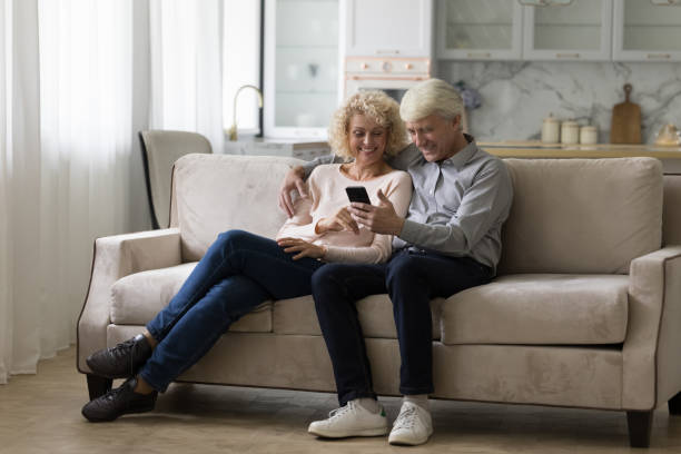 istock Happy joyful senior husband and wife using smartphone at home 1423172355