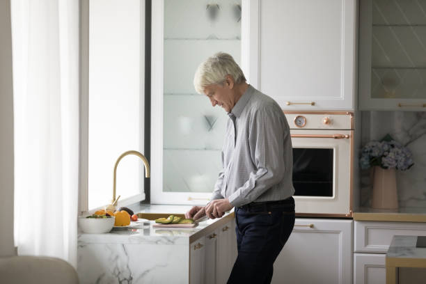 istock Older retired homeowner man cooking salad in modern kitchen 1423172419
