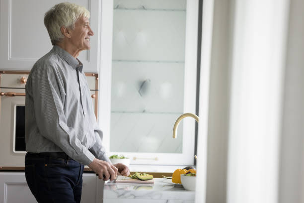 istock Cheerful dreamy senior man enjoying cooking in modern home kitchen 1423172424