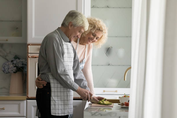 istock Happy senior husband cooking salad in kitchen, getting hug 1423172427