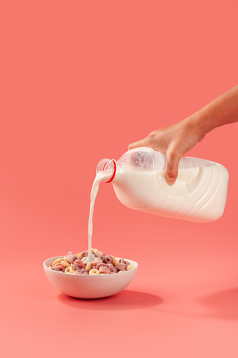 Woman pouring milk into a bowl of cereal