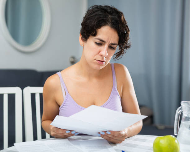 istock Frustrated brunette woman is unhappy with payment document for utilities 1423174692