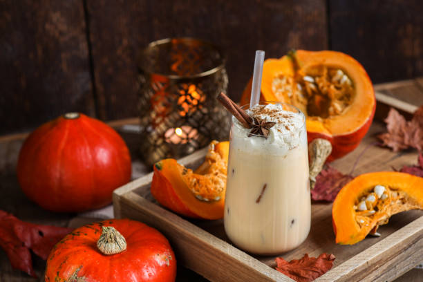 boisson au lait frappé au latte aux épices à la citrouille avec crème fouettée et épices à la cannelle dans une cuisine rustique en bois - latté pumpkin spice coffee photos et images de collection