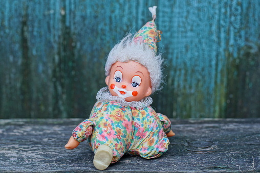 one small colored clown toy sits on a gray table near a green wooden wall