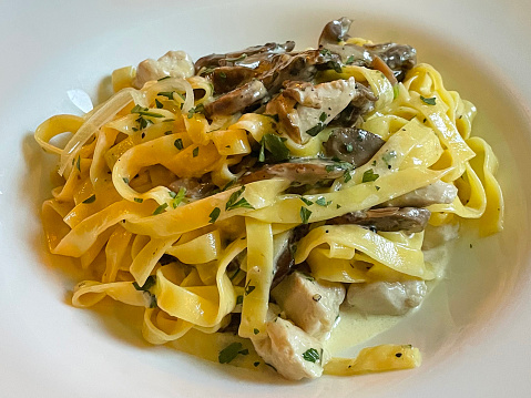 Stock photo showing elevated view of an Italian creamy chicken and mushroom tagliatelle recipe dish dining out at restaurant.