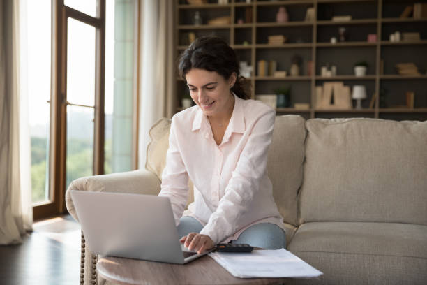 istock Young woman sit on sofa working or studying on laptop 1423181288